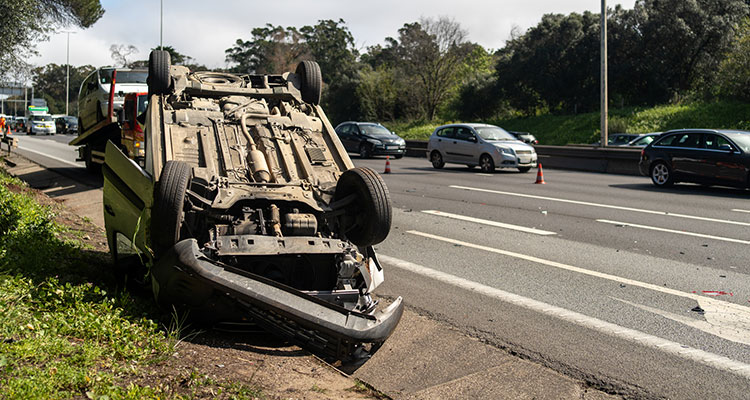 Wrecked car lying upside down on the roadside after a crash, representing serious injuries from Minnesota highway work zone accidents.
