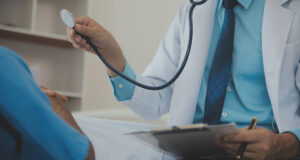 Doctor sitting at the bedside of a male patient in a hospital, representing how pre-existing conditions are evaluated in a Minnesota personal injury case.