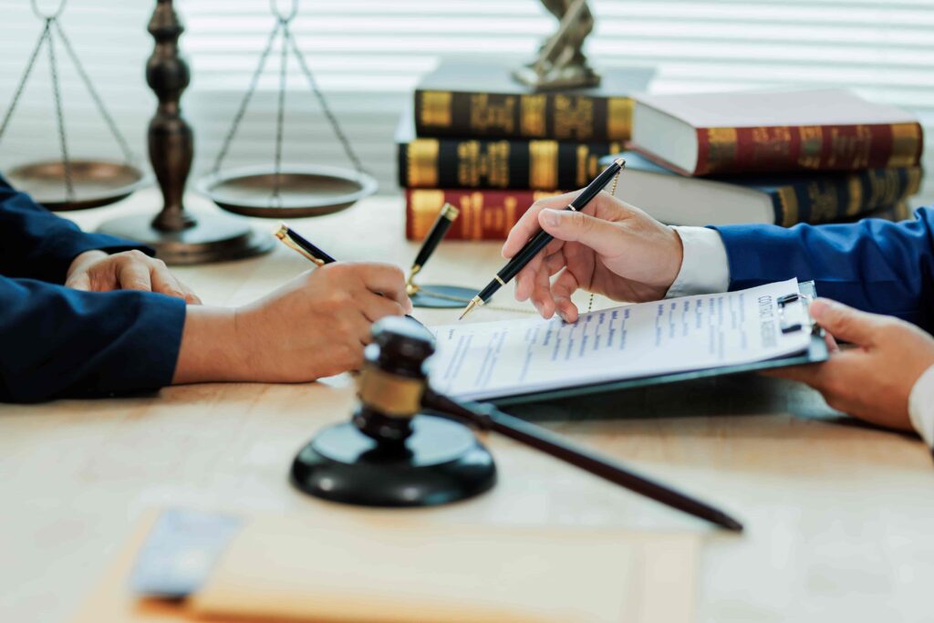Attorney reviewing and explaining a legal contract to a client at a desk with law books, gavel, and scales of justice, representing legal consultation and agreement.