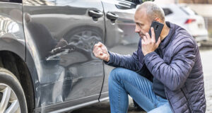 Damages in drunk driving accident Angry driver calling the insurance company next to a damaged car, illustrating uninsured and underinsured motorist claims in Minnesota.