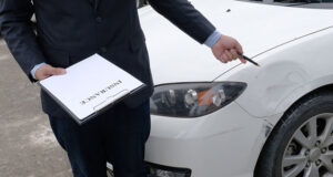 Insurance adjuster inspecting a damaged car after a crash, representing how uninsured and underinsured motorist coverage works in Minnesota.