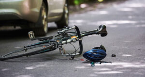 Damaged bicycle and car after a collision on a road, illustrating a Minneapolis bicycle accident and the vehicle-versus-cyclist crashes that often lead to injury claims.