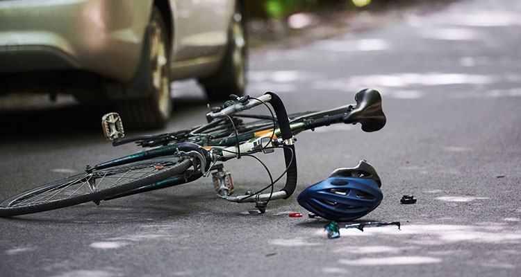 Damaged bicycle and car after a collision on a road, illustrating a Minneapolis bicycle accident and the vehicle-versus-cyclist crashes that often lead to injury claims.