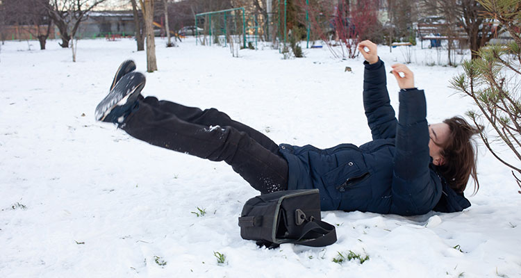 Woman falling on icy snow-covered ground in winter, representing Minnesota slip and fall injuries and potential liability for unsafe property conditions.